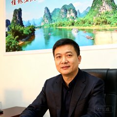 桂林漓江景区运营总监张明远在办公室内的半身肖像照，背景是景区风光海报